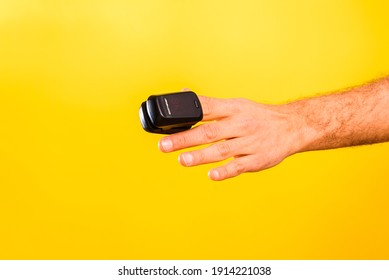 Oximeter on a finger of a patient, isolated on yellow background. - Shutterstock ID 1914221038