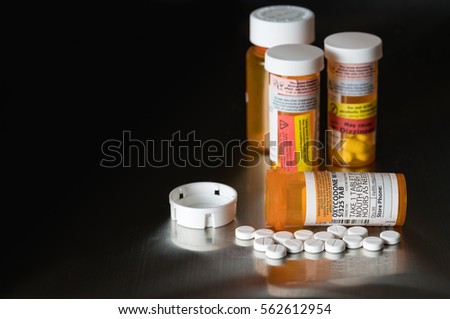 Oxycodone is the generic name for a range of opoid pain killing tablets. Prescription bottle for Oxycodone tablets and pills on metal table for opioid epidemic illustration