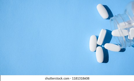 Oxycodone pills. Opioid pain medication, narcotic. Close up white pills with a bottle on a blue background