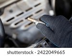 Oxygen sensor for gasoline and diesel engines in the hand against car engine. Mechanic holds oxygen sensor. lambda probe.