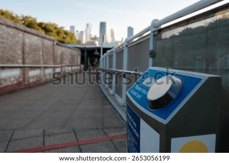 Oyster card reader machine is counting passengers entering and exiting cutty sark dlr station, located in greenwich, london, with canary wharf skyline in the background