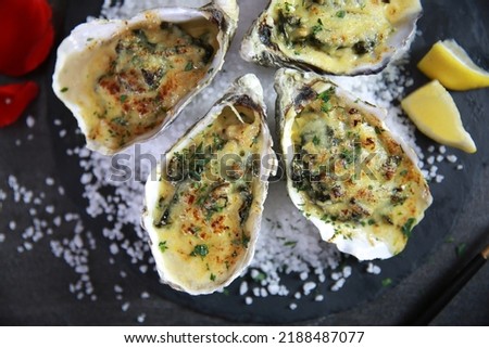 Oyster Rockefeller bake fresh oysters with creamy sauce on top appetiser romantic dinner on black plate dark background