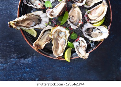 Oyster season. Fresh oysters are placed on a round plate with ice and lime. Seafood on a plate. Oyster on the half shell. Two varieties of oysters. Top view.