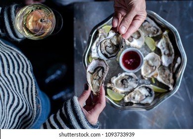 Oyster Spring/summer Party. Fresh Oysters With Lemons On The Ice With Red Sauce Served On The Metal Dish, On The Ice. Woman And Man Cheers Oysters With Champaign  