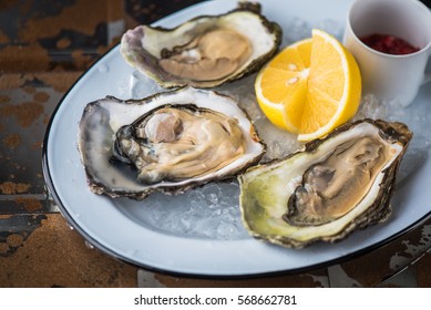 Oysters on a white plate - tasty and healthy. Seafood close-up on a dark background.
