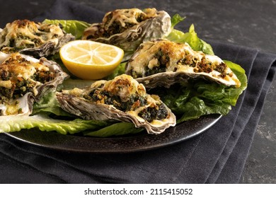 Oysters Rockefeller baked with spinach and cheese, served on a dark plate with lemon and lettuce, selected focus, narrow depth of field