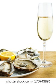 Oysters in a white plate with lemon and a glass of wine on a wooden table isolated on white