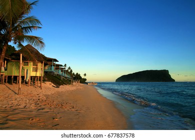 Pacific Island Tropical Sandy Beach With Traditional Beach Fales Resort Accommodation During Beautiful Colourful Sunset Sky Twilight, Samoan Islands