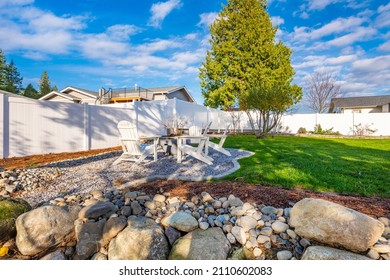 Pacific Northwest backyard and spacious deck bright sunny day with blue skies fire pit fireplace white Adirondack chairs green grass fenced family home
