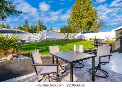 Pacific Northwest Backyard And Spacious Deck Bright Sunny Day With Blue Skies Fire Pit Fireplace White Adirondack Chairs Green Grass Fenced Family Home