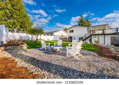 Pacific Northwest Backyard And Spacious Deck Bright Sunny Day With Blue Skies Fire Pit Fireplace White Adirondack Chairs Green Grass Fenced Family Home