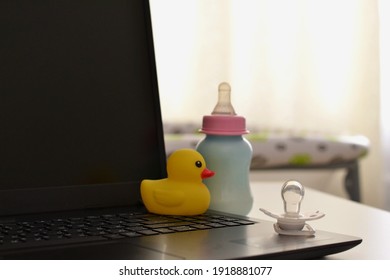 Pacifier on the laptop and baby bottle. 
Working in a decree. Maternity leave concept. 