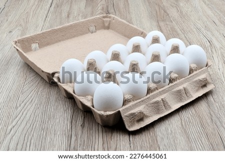 Pack of 15 white eggs in an egg packaging carton box, isolated on wooden table