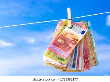 Pack Of Banknotes Of Foreign Currencies Hanging On A Wooden Clothespin Against A Blue Sky. Cash Of Money. Laundering Money. Background Of Global Economy, World Trade And International Crime.