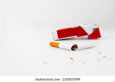 A pack of cigarettes on a white background and a broken cigarette in the foreground. Anti-smoking concept. harm of smoking
