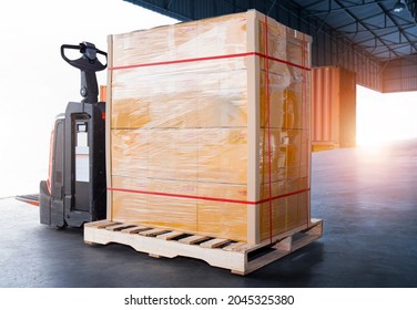 Package Boxes Wrapped Plastic Film On Pallet With Electric Forklift Pallet Jack. Supply Chain. Cargo Shipment Boxes. Warehouse Shipping Logistics And Transportation.	
