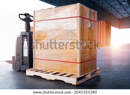 Package Boxes Wrapped Plastic Film on Pallet with Electric Forklift Pallet Jack. Supply Chain. Cargo Shipment Boxes. Warehouse Shipping Logistics and Transportation.	
