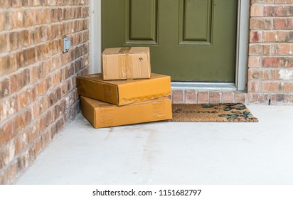 Package Delivery On Doorstep. Boxes And Postal Delivery On Modern Brick Home Doorstep On Front Green Painted Door