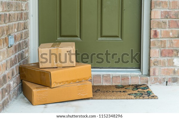 Package delivery on\
doorstep. Boxes and postal delivery on modern brick home doorstep\
on front porch