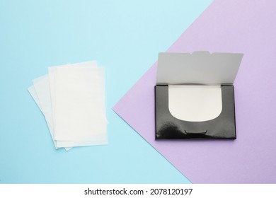 Package with facial oil blotting tissues on color background, flat lay. Mattifying wipes