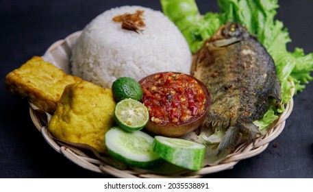 A Package Of Rice, Fried Fish And Fresh Vegetables.