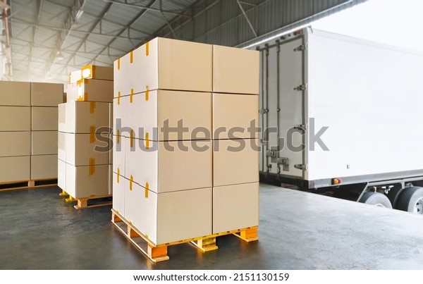 Packaging Boxes Stacked on Pallets Load with\
Shipping Cargo Container. Delivery Trucks Loading at Dock\
Warehouse. Supply Chain. Shipment Boxes. Distribution Warehouse\
Freight Truck Transport\
Logistics