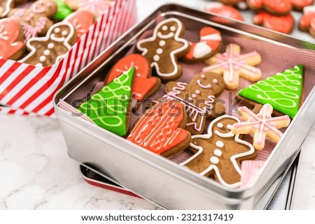 Packaging a homemade variety of fudge and gingerbread cookies for Christmas food gifts into tin boxes.