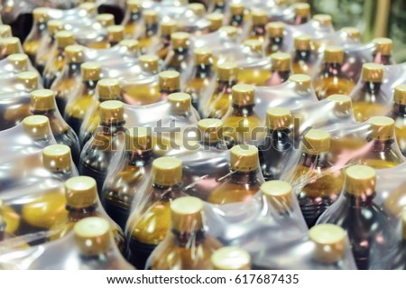 Packaging plastic bottles at the brewery. Packed shrink packaging film.