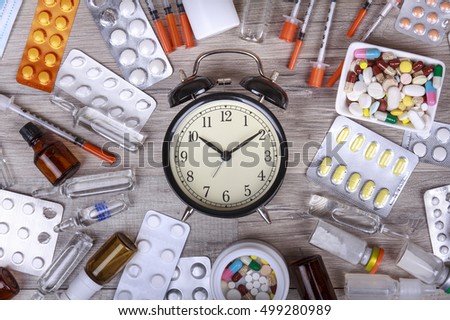 Packaging of tablets and pills on the table with clock in the middle. Medicine