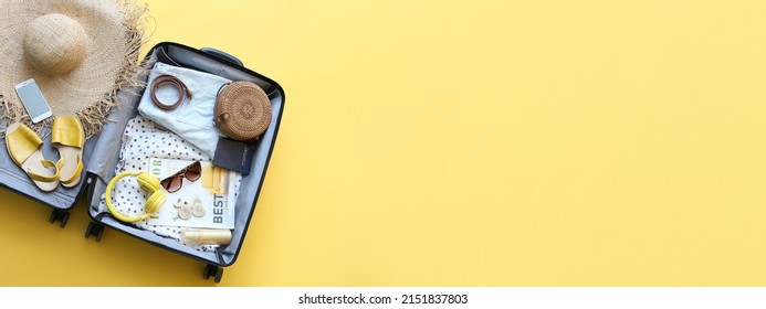 Packed suitcase with belongings on yellow background with space for text - Shutterstock ID 2151837803