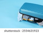 Packed suitcase full of clothes on light blue background, closeup. Space for text