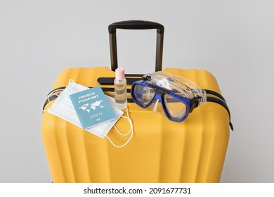 Packed Suitcase With Immune Passport, Medical Masks, Sanitizer And Snorkeling Mask On Grey Background