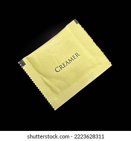 A Packet Of Dairy Creamer Isolated On A Black Background.