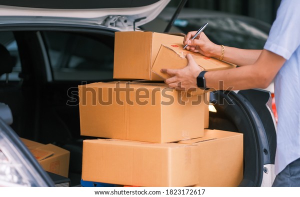 Packing and check product\
at car rear trunk by Asian man online seller. Concept startup small\
business online selling, e-commerce, packing and delivery shipping\
product.