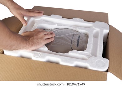 Packing goods in cardboard box with styrofoam material for safe transportation of cargo. Isolated on white background. Man's hands are packing the goods.