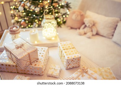 A lot of packing handmade gift boxes lying on the table near Christmas tree in the midst of golden lights, glowing garland, candle. Soft focus - Shutterstock ID 2088073138