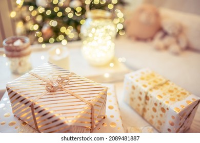 A lot of packing handmade gift boxes lying on the table near Christmas tree in the midst of golden lights, glowing garland, candle. Soft focus - Shutterstock ID 2089481887