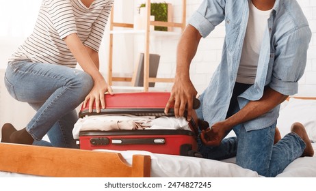 Packing suitcase. Couple trying to close valise, preparing for honeymoon - Powered by Shutterstock