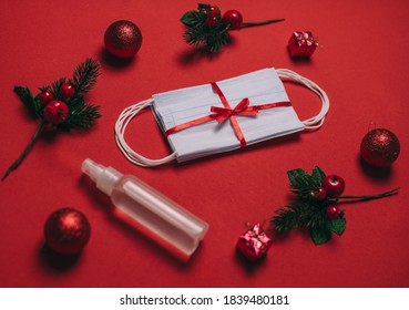 Packing of white medical surgical masks, Christmas present under the Christmas tree on a red background and sanitizer. Coronavirus pandemic, quarantine, 2020, 2021. Celebrating the new year, stay home - Powered by Shutterstock