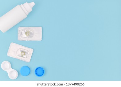 Packs With Hazel Green Colored Circle Lenses, A Type Of Contact Lenses To Enlarge Eyes And Change Eye Color With Storage Container And Cleaning Solution On Side Of Blue Background With Copy Space