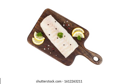 Packshot. Cod fillet on a wooden board, decorated with lemon, parsley and spices.