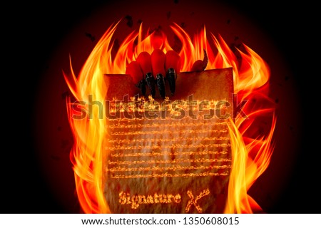 Pact to sell your soul to Lucifer, strike a Faustian bargain or deal with the devil concept theme with Satan holding in creepy ugly red hand with claws burning scroll with fiery text written in flames