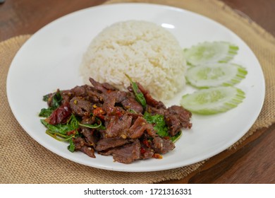 Pad Kra Pao Beef - Stir fried beef with holy basil on Sack cloth above the wooden table - Horizontal
