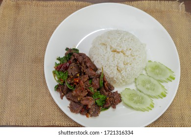 Pad Kra Pao Beef - Stir fried beef with holy basil on Sack cloth above the wooden table - Horizontal