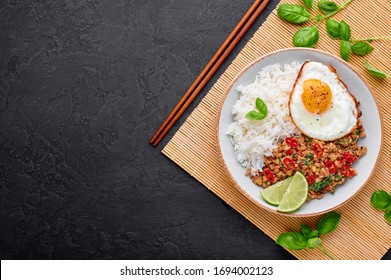 Pad Krapow Gai - Thai Basil Chicken with Rice and fried Egg black slate background. Pad Krapow is Thai cuisine dish with minced chicken or pork meat, basil, soy and oyster sauces. Thai Food Copy space