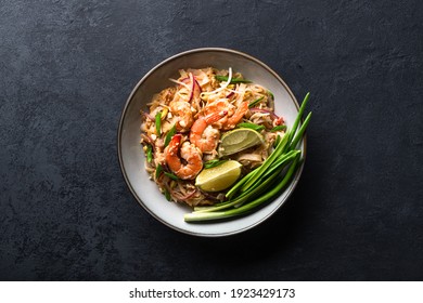 Pad Thai with shrimp and vegetables on a dark background, view from above