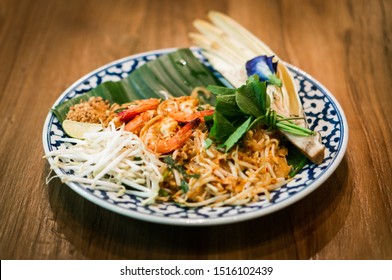 Pad Thai. Thai style fried noodles with shrimps and vegetables beautifully decorated in plate on wooden table. Thai fried noodle with prawns. Traditional  Thai food menu for restaurant. Isolated.
