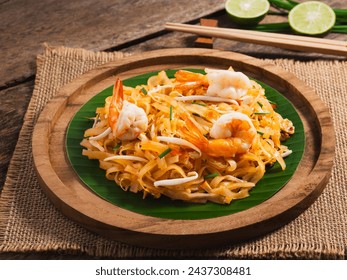 Pad Thai-Stir fried rice noodles with shrimp and sauce in plate on wooden table background. Thai street food