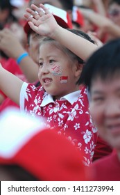 Padang, Singapore / Singapore - August 9, 2005 : A Little Girl With Singapore Flag On Her Cheek And People Around Her Waving Their Hands Up For Cheering On Singapore National Day 2005.