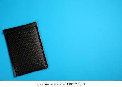 Padded envelope with bubble wrap on light blue background, top view. Space for text